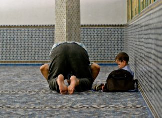 Musulmano che prega alla moschea con bambino