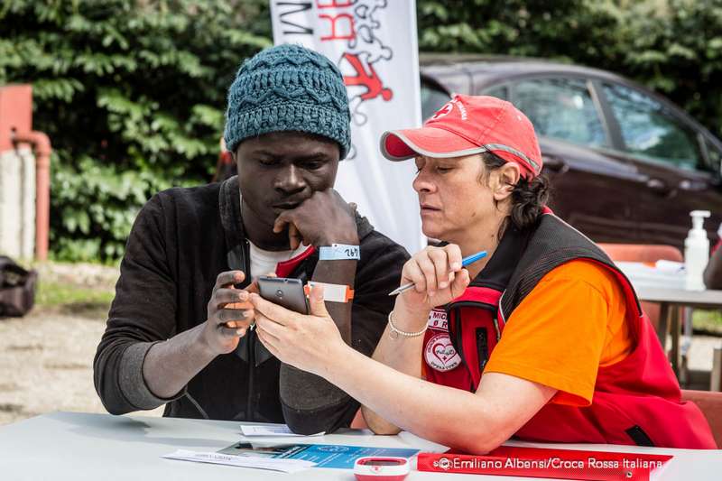 Un'operatrice Croce Rossa aiuta un migrante a comporre il numero di telefono. Migranti telefonano alle famiglie dal camper della Croce Rossa. Foto: Emiliano Albensi