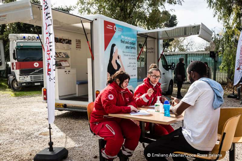 Volontarie Croce Rossa parlano con un ragazo migrante vicino al tracing bus. Migranti telefonano alle famiglie dal camper della Croce Rossa. Foto: Emiliano Albensi